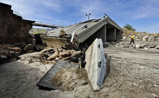 A worker walks near a washed-out bridge near the town of Desert Center, along Interstate 10 in Southern California, on Monday, July 20, 2015. (Photo by Nick Ut/AP Photo)