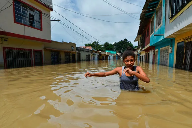 A girl wades through flooding due to the overflowing of the Cauca River after heavy rains, in a street of Cali, Cauca Valley, Colombia, 13 May 2017. Flooding and mudslides in Colombia have killed several people and affected thousands in the past weeks. Authorities issued a red alert as eight municipalities of the region have been affected by flooding. (Photo by Luis Robayo/Getty Images)