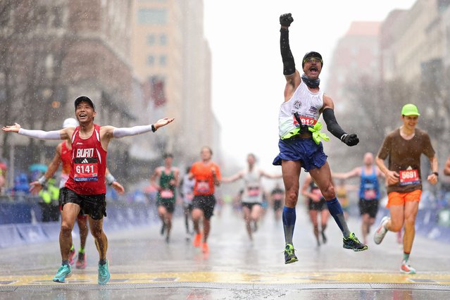 Fernando Ferreira celebrates in the rain as he crosses the finish line next to Zhenfei Lu (L) during the 127th Boston Marathon on April 17, 2023 in Boston, Massachusetts. (Photo by Maddie Meyer/Getty Images)