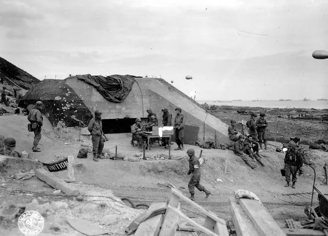 U.S. Army troops congregate around a signal post used by engineers on the site of a captured German bunker overlooking Omaha Beach after the D-Day landings near Saint Laurent sur Mer, June 7, 1944. REUTERS/US National Archives
