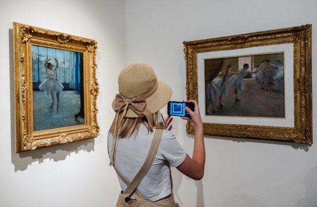 A woman takes a picture of a painting during the “Impressionists instead of heat” campaign, which offers free admission to the Gallery of 19th and 20th Century European and American Art of the State Pushkin Museum in the hottest daytime hours, in Moscow, Russia on July 17, 2024. (Photo by Maxim Shemetov/Reuters)