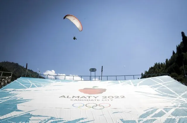 A paraglider flies over a banner promoting Almaty candidate city for 2022 Winter Olympic Games at the Medeu skating oval in Almaty, Kazakhstan, July 26, 2015. Kazakhstan is aspiring to host the 2022 Winter Olympics but many in the Central Asian nation view the bid as yet another vanity project of long-ruling President Nursultan Nazarbayev. Almaty, the financial capital, will go head-to-head with the Chinese metropolis Beijing on Friday when the International Olympic Committee elects the winner at its session in Malaysia. (Photo by Shamil Zhumatov/Reuters)