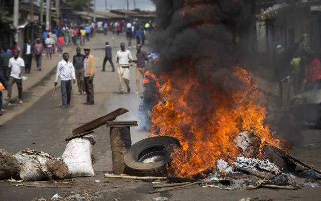 Protesters carrying sticks and rocks stand behind a barricade of burning tyres, as they call for the disbandment of the national electoral commission over allegations of bias and corruption, in the Kibera slum of Nairobi, Kenya Monday, June 6, 2016. (Photo by Ben Curtis/AP Photo)