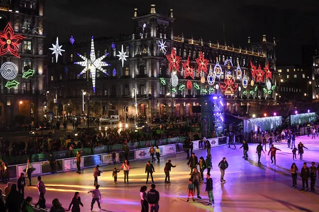 People skate on an acrilic rink placed in the Zocalo square with the City Hall showing Christmas decorations in the background in Mexico City on December 17, 2019. (Photo by Pedro Pardo/AFP Photo)