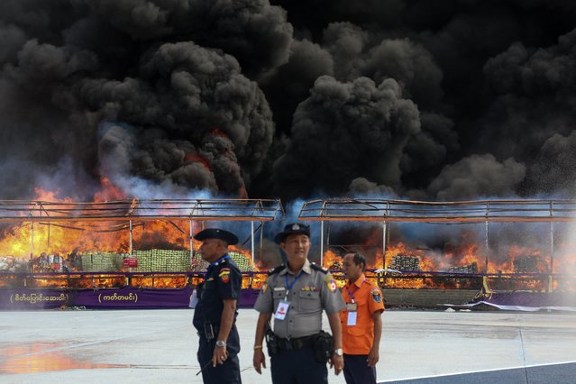 Officials stand in front of a burning pile of seized illegal drugs during a destruction ceremony to mark the UN's “International Day against Drug Abuse and Illicit Trafficking” in Yangon on June 26, 2024. (Photo by AFP Photo/Stringer)