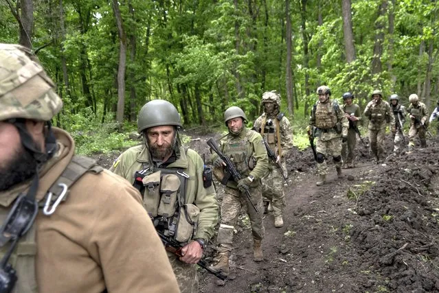 Ukrainian servicemen walk in the forest near a recently retaken village, north of Kharkiv, east Ukraine, Sunday, May 15, 2022. (Photo by Mstyslav Chernov/AP Photo)