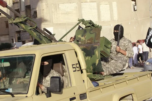 Militant Islamist fighters travel in a vehicle as they take part in a military parade along the streets of Syria's northern Raqqa province June 30, 2014. (Photo by Reuters/Stringer)