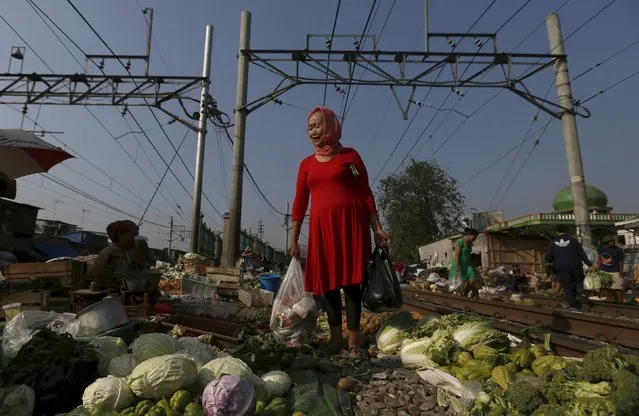 A woman holds plastic bags while browsing at a vegetable market located on train tracks near Duri train station in Jakarta, Indonesia August 3, 2015. (Photo by Reuters/Beawiharta)