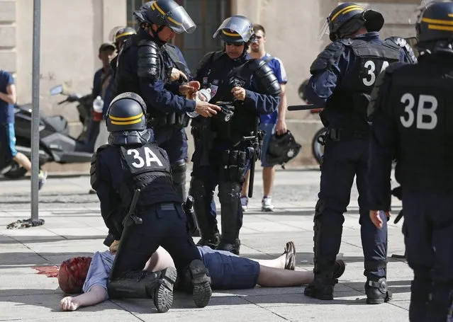 An man injured in clashes is assisted by police officers in downtown Marseille, France, Saturday, June 11, 2016. (Photo by Darko Bandic/AP Photo)