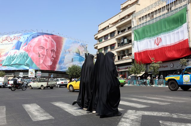 Veiled Iranian women walk past to a huge billboard of late Iranian Hamas leader Ismail Haniyeh and late Iranian Quds forces commander Ghasem Soleimnai at Enghelab Square in Tehran, Iran, 27 August 2024. Tension remains high between Iran and Israel since Ismail Haniyeh was killed in Tehran on 31 July 2024. According to the official news agency Irna, newly appointed Iranian Foreign Minister Abbas Araghchi said on 26 August that Iran will respond against Israel in retaliation for the killing of Haniyeh. (Photo by Abedin Taherkenareh/EPA/EFE)