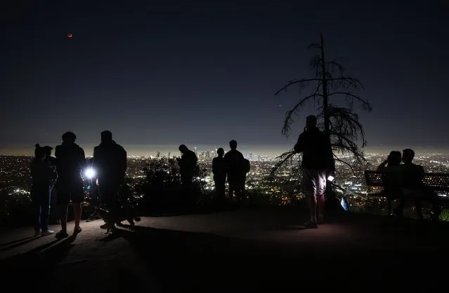 People take in the view from Griffith Park while a total lunar eclipse creates a “super blood moon” on May 15, 2022 in Los Angeles, California. The eclipse coincided with a super moon which occurs when the moon is at its closest point to earth. (Photo by Mario Tama/Getty Images)