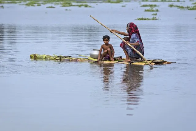 A flood-affected woman with a child rows her makeshift banana rafrt towards safer areas from marooned Tarabari village, in the northeastern Indian state of Assam, Monday, June 20, 2022. Early and strong monsoon rains have brought heavy flooding to northeastern India and Bangladesh, killing dozens of people, forcing hundreds of thousands from their homes and cutting millions off from crucial supplies. (Photo by Anupam Nath/AP Photo)