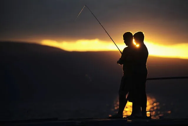 A boy casts his fishing line on the bank of Lake Ohrid in village of Trpejica during a stormy evening July 16, 2014. (Photo by Ognen Teofilovski/Reuters)