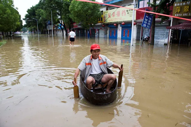 A resident rows a makeshift boat to make his way at a flooded street in Chaohu, Anhui Province, China, July 2, 2016. (Photo by Reuters/China Daily)