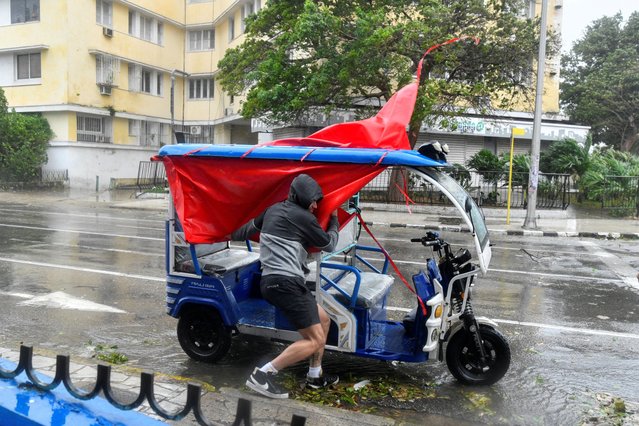 A man tries to hold his tricycle taxi on the street as Hurricane Rafael passes by Havana, Cuba, on November 6, 2024. (Photo by Norlys Perez/Reuters)