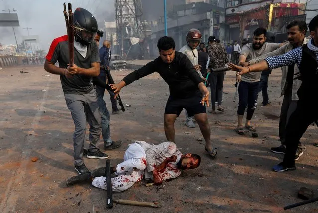 People supporting the new citizenship law beat a Muslim man during a clash with those opposing the law in New Delhi, India, February 24, 2020. A policeman was killed and dozens of people injured amid clashes in New Delhi as thousands demonstrating for and against a new citizenship law rioted for several hours before U.S. President Trump's maiden visit to the city. (Photo by Danish Siddiqui/Reuters)