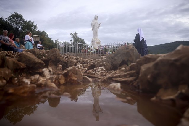 Pilgrims pray next to the statue of Virgin Mary on the Hill of appearance where it is believed that Virgin Mary showed herself and conveyed messages of peace to six children in Medjugorje, Bosnia, Thursday, September 19, 2024. (Photo by Armin Durgut/AP Photo)