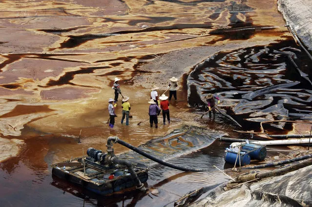 Labourers work to drain sewage water from a leaked sewage tank at a copper mine in Shanghang, Fujian province, July 13, 2010. The sewage leak from the copper mine owned by Zijin Mining Group Co, whose shares were suspended from trading in Hong Kong on Monday, has polluted a river and reservoir in Fujian province, Xinhua news agency reported. Xinhua cited environmental authorities as saying the leak from a plant of the Zijinshan Copper Mine had killed or poisoned about 1.89 million kg of fish. (Photo by Reuters/Stringer)