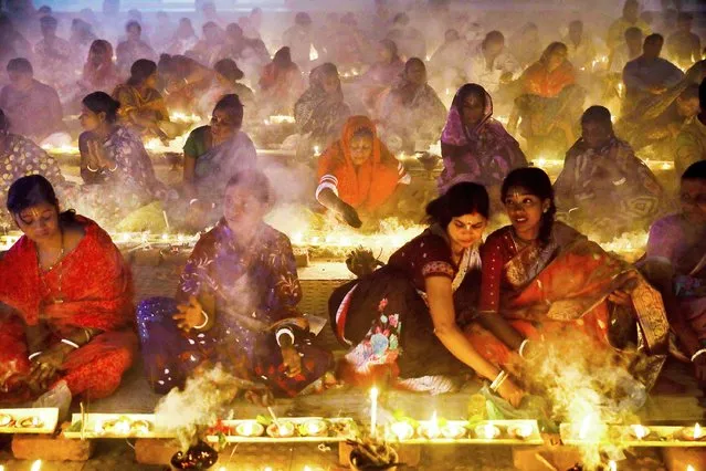 Hindu devotees sit together on the floor of a temple with oil lamps, praying to Lokenath Brahmachari, a Hindu saint, as they observe Rakher Upabash, in Narayanganj, Bangladesh, November 6, 2021. (Photo by Mohammad Ponir Hossain/Reuters)