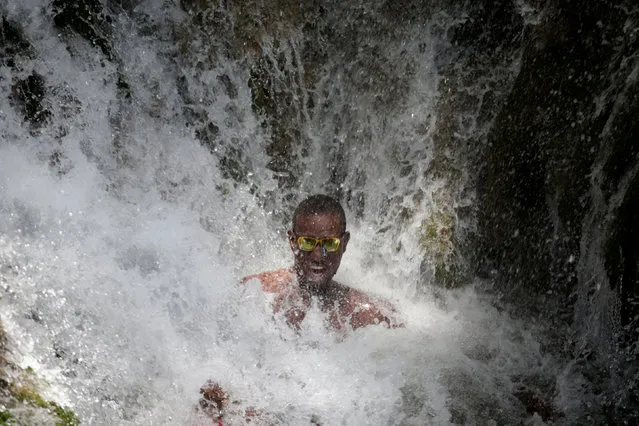 A pilgrim takes a bath during the celebration of an annual pilgrimage to the waterfall in Saut D'Eau, Haiti, July 16, 2016. Pilgrims bath in the waterfall that is believed to have healing and purifying powers and according to a legend the Virgin Mary appeared atop a palm tree at this site. (Photo by Andres Martinez Casares/Reuters)