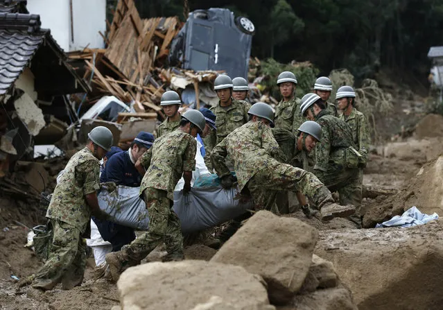 Japan Self-Defense Force (JSDF) soldiers and police officers carry the body of a victim in a plastic bag at a site where a landslide swept through a residential area at Asaminami ward in Hiroshima, western Japan, August 20, 2014. (Photo by Toru Hanai/Reuters)