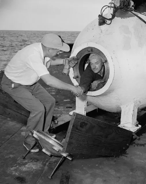 Dr. Otis Barton leans out of his benthoscope and shakes hands with Dr. Maurice Nelles, just before he was sealed in and lowered into the ocean at Smuggler's Cove, Calif., August 15, 1949. He descended to 2,300 feet on that particular descent, but was forced to return to the surface because of a power failure. (Photo by AP Photo)