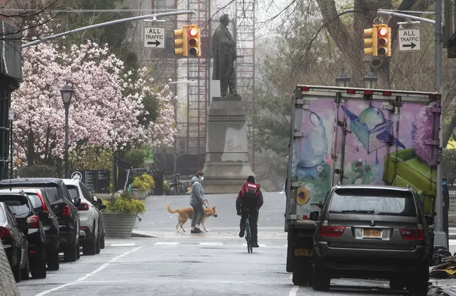 A cyclist and a dog walker are seen along West 16th Street near Union Square, Sunday, March 29, 2020, in New York. (Photo by Mary Altaffer/AP Photo)