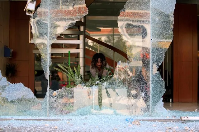 A worker cleans up broken glass from a bank facade after overnight protests against growing economic hardship in Sidon, Lebanon April 29, 2020. (Photo by Ali Hashisho/Reuters)