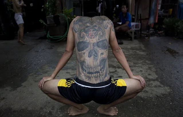 In this Tuesday, July 14, 2015, photo, Phoe Thaw, center, a member of the White New Blood lethwei fighters club, a Myanmar traditional martial-arts club which practices a rough form of kickboxing, stretches during a practice session in their gym on a street in Oakalarpa, north of Yangon, Myanmar. (Photo by Gemunu Amarasinghe/AP Photo)