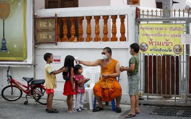 A Thai Buddhist monk takes the temperature of kids entering the Wat Molilokayaram in Bangkok, Thailand, 27 April 2020. The ongoing coronavirus and COVID-19 pandemic has forced people to adjust their daily routines after governments worldwide imposed travel restrictions, quarantine measures, curfews and lockdowns to stem the spread of the SARS-CoV-2 coronavirus which causes the COVID-19 disease. (Photo by Diego Azubel/EPA/EFE/Rex Features/Shutterstock)