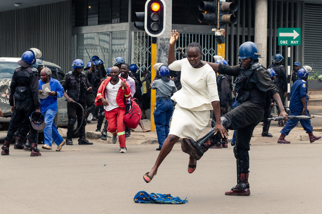 An anti-riot police man in Zimbabwe tackles a woman with his boot as they dispersed a crowd gathered to hear an address by leader of the MDC (Movement for Democratic Change) Alliance, Nelson Chamisa at Morgan Tsvangirai House, the party headquarters, in Harare, on November 20, 2019. Nelson Chamisa was due to address party supporters in his Hope of the Nation Address (HONA). The public address was blocked by riot police who beat up several people as they dispersed MDC supporters and other curious onlookers. (Photo by Jekesai Njikizana/AFP Photo)