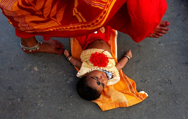 A Hindu woman steps over a child in a ritual seeking blessings for the child from the Sun god during the religious festival of Chhath Puja in Kolkata, India October 26, 2017. (Photo by Rupak De Chowdhuri/Reuters)