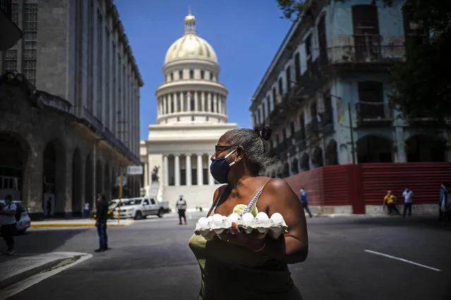 A woman wearing a face mask as a precaution amid the spread of the new coronavirus carries eggs past the Capitol building in Havana, Cuba, Tuesday, June 16, 2020. (Photo by Ramon Espinosa/AP Photo)