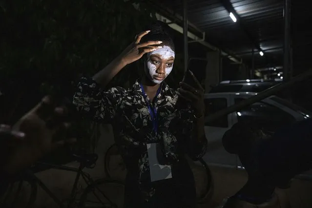 Models use their phone lights during a power outage to put on make-up before the start of the third Ouaga Fashion Week Friday May 13, 2022 in Ouagadougou, Burkina Faso. Ouaga Fashion Week returned to the Burkinabe capital after a two year COVID-19 related break. (Photo by Sophie Garcia/AP Photo)