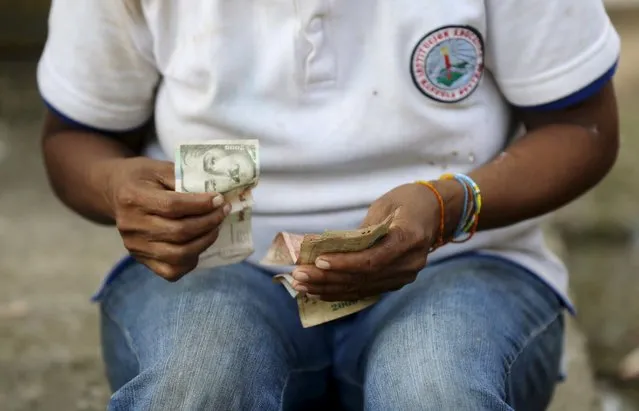 A Colombian Nukak Maku Indian woman counts money at a park in San Jose del Guaviare of Guaviare province September 4, 2015. (Photo by John Vizcaino/Reuters)