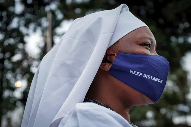 A worshipper of Legio Maria wears a protective face mask with the lettering “Keep distance” as she arrives to attend a prayer at their church in the Kibera slum of Nairobi, on July 26, 2020, after Kenya's President allowed places of worship to reopen under strict guidelines to curb the spread of the novel coronavirus (COVID-19). (Photo by Yasuyoshi Chiba/AFP Photo)