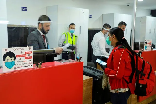 Departing passengers check-in luggage at the counter at Sulaimaniya International Airport in Iraq's autonomous Kurdish region on August 2, 2020, as the airport resumes flight operations following the COVID-19 lockdown. (Photo by Shwan Mohammed/AFP Photo)