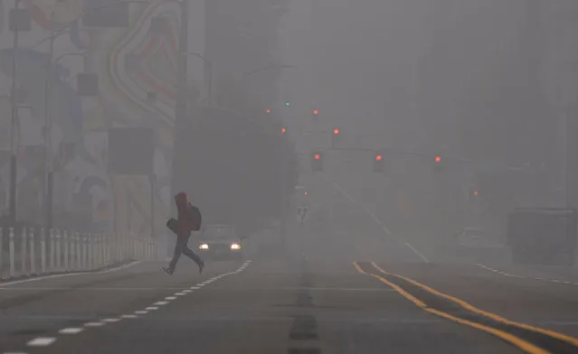 A man crosses a street in downtown Portland, Oregon where air quality due to smoke from wildfires was measured to be amongst the worst in the world, September 14, 2020. The deadly fires spreading across three western US states are causing record-breaking pollution and a spate of health woes, from headaches and coughs to impaired vision, that have residents worried about the long-term consequences Portland, the largest city in Oregon, has been blanketed for days by a dense smog that has sent pollution meters soaring. (Photo by Robyn Beck/AFP Photo)