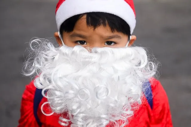 A boy wearing a Santa Claus costume poses for a picture ahead of Christmas celebrations at a primary school, in Ayutthaya, Thailand on December 23, 2022. (Photo by Chalinee Thirasupa/Reuters)