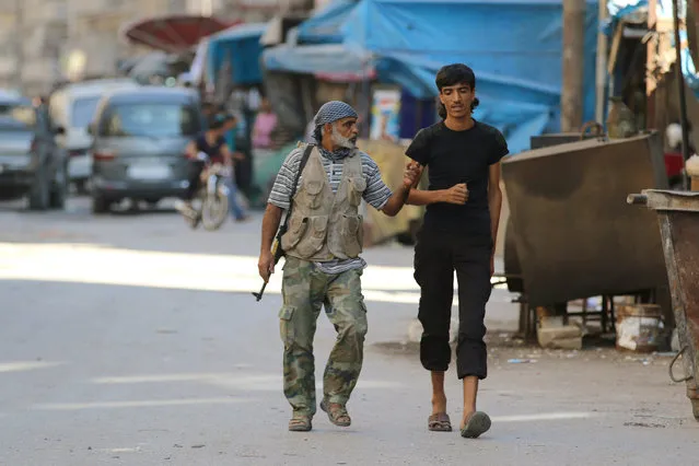 Rebel fighters walk inside a market in the rebel-held al-Shaar neighbourhood of Aleppo, Syria, September 17, 2016. (Photo by Abdalrhman Ismail/Reuters)