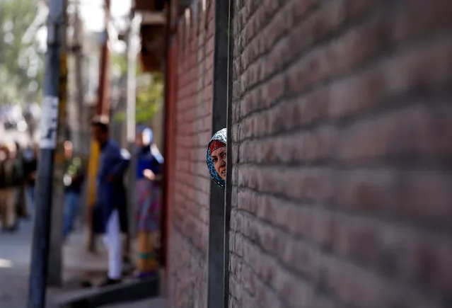 A woman looks out from a door during a protest in Srinagar, against the recent killings in Kashmir region, September 25, 2016. (Photo by Danish Ismail/Reuters)