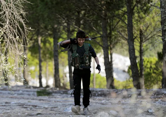 Turkish-backed Free Syrian Army fighter walks as he holds his weapon in Eastern Afrin, Syria, February 13, 2018. (Photo by Khalil Ashawi/Reuters)