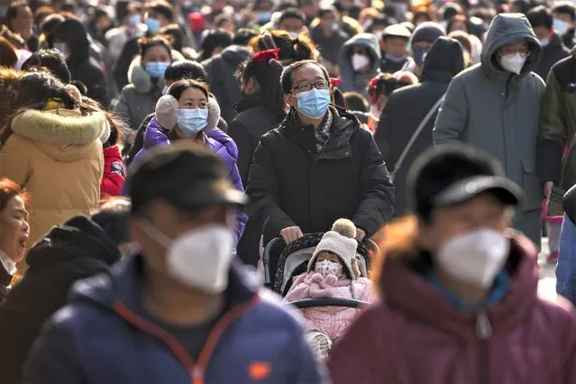 Visitors wearing face masks tour at Qianmen pedestrian shopping street on the first day of the Lunar New Year holiday in Beijing, Sunday, January 22, 2023. (Photo by Andy Wong/AP Photo)
