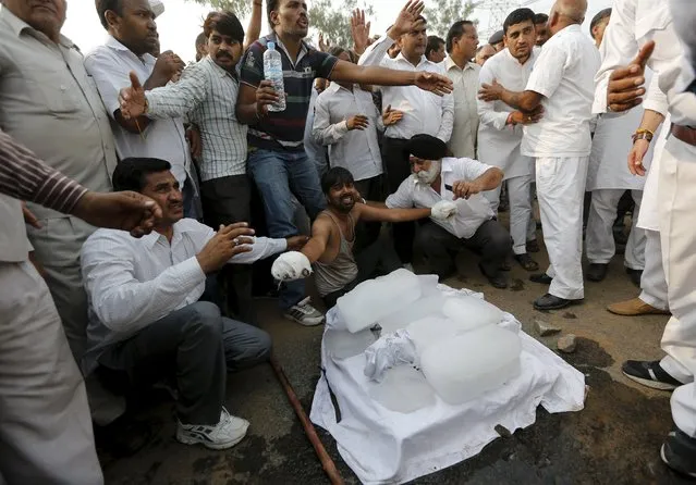The father (bottom C) of two children who were burnt alive, with his hands bandaged, wails next to the bodies of his children wrapped in white shrouds, as he along with other villagers block a national highway during a protest against the crime at Ballabhgarh in the northern state of Haryana, India, October 21, 2015. (Photo by Adnan Abidi/Reuters)