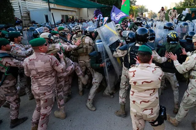 Riot police scuffle with demonstrators protesting against the burning of a Koran in Stockholm outside the Swedish embassy in Baghdad on January 23, 2023. (Photo by Ahmad Al-Rubaye/AFP Photo)