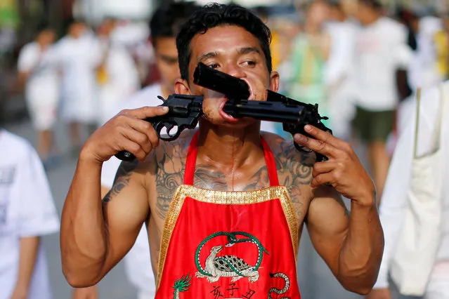 A devotee of the Chinese Samkong Shrine walks with two revolvers pierced in his mouth during a procession celebrating the annual vegetarian festival in Phuket, Thailand Octuber 4, 2016. (Photo by Jorge Silva/Reuters)
