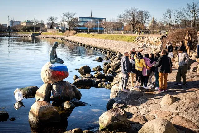 People gather for photos next to the Little Mermaid sculpture that was vandalized with colours painted of the Russian flag in Langelinie, Copenhagen, Denmark on March 2, 2023. (Photo yb Ida Marie Odgaard/Ritzau Scanpix via Reuters)
