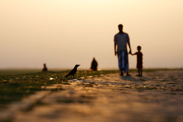 People are silhouetted as they watch a bird while walking along the bank of Padma river in the afternoon, in Munshiganj, Bangladesh on May 27, 2025. (Photo by Mohammad Ponir Hossain/Reuters)