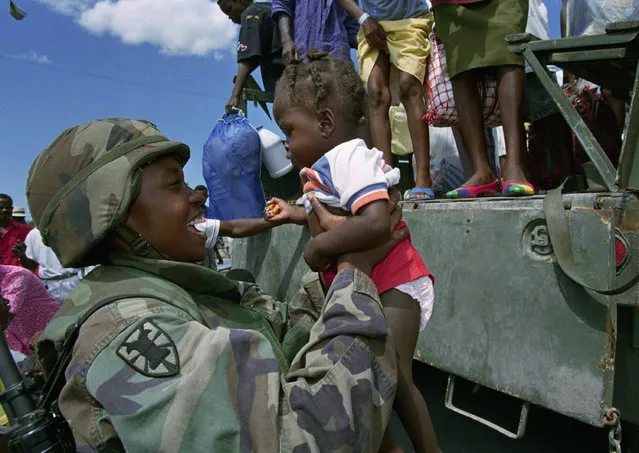 U.S. Army Spc. Corliss Young of Ft. Eustis, Va., helps a young Haitian girl off a truck filled with some of the 505 Haitians repatriated to Port-au-Prince, Tuesday, October 18, 1994, from Guantanamo Naval Base. This was the first group of Haitian repatriated since President Jean-Bertrand Aristide's arrival last Saturday. (Photo by Lynne Sladky/AP Photo)