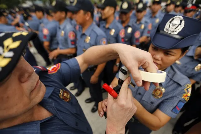Filipino Police Regional Director Carmelo Valmoria (L)  tapes the muzzle of a gun at a police camp in Taguig City, south of Manila, Philippines, 22 December 2014. (Photo by Francis R. Malasig/EPA)